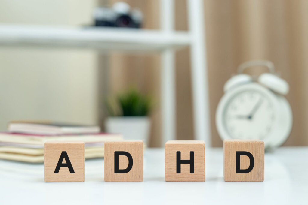 ADHD spelled in wooden blocks on a desk, adhd teeth grinding article featured image