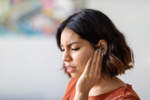 woman with ear pain from grinding teeth, discovering the link between tmj, bruxism and tinnitus featured image